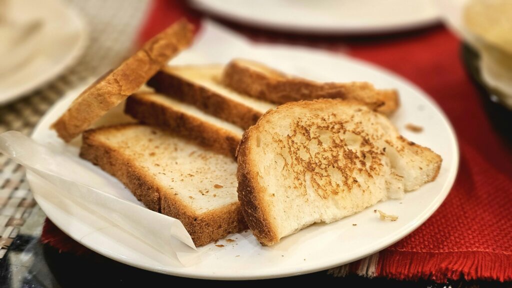 Appetizing close-up of toasted bread slices on a white plate indoors.