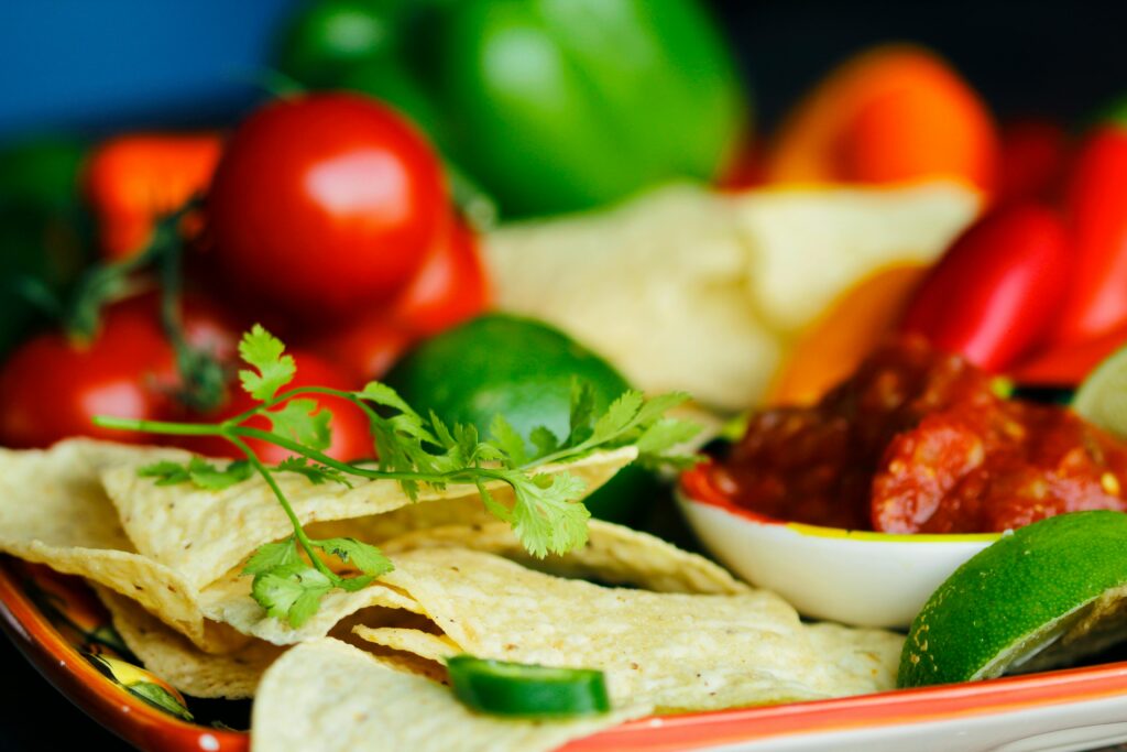 Fresh Mexican snack platter with tortilla chips, salsa, tomatoes, lime, and peppers.